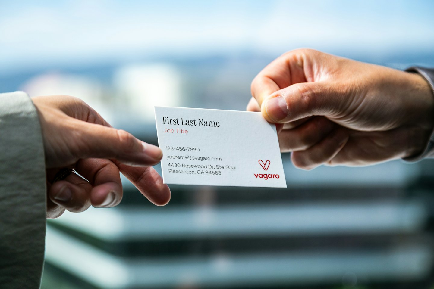 Zwei Personen tauschen im Büro eine weiße Visitenkarte aus.