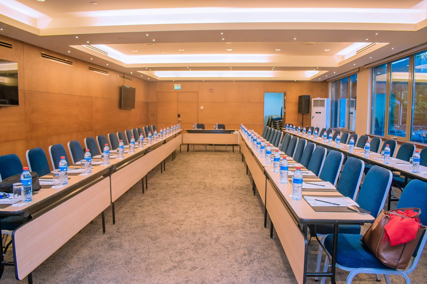 Moderner Konferenzraum mit Holztischen, die für ein Meeting angeordnet sind.